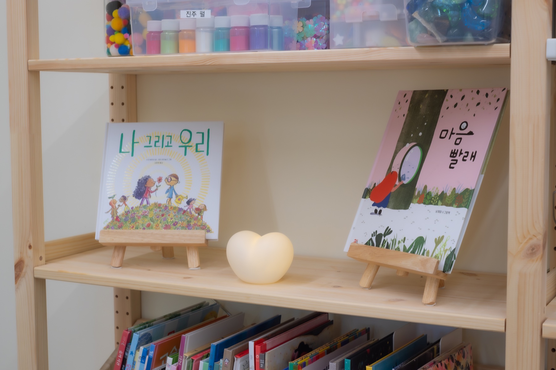 그림책과 하트 모양 조명이 놓인 원목 책장